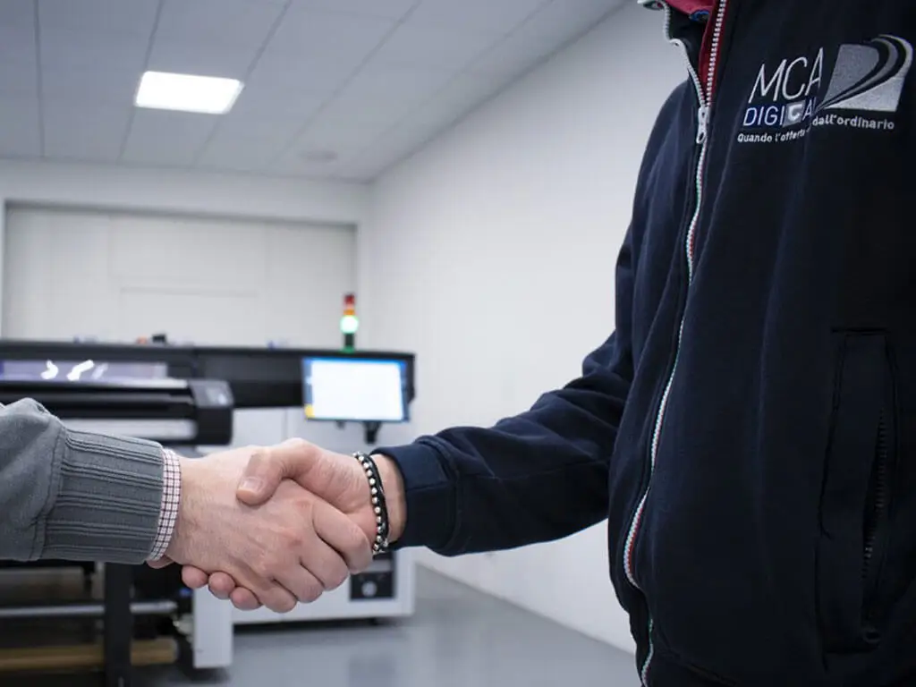 Foto dov'è possibile vedere la stretta di mano tra un tecnico MCA e un cliente dopo un intervento